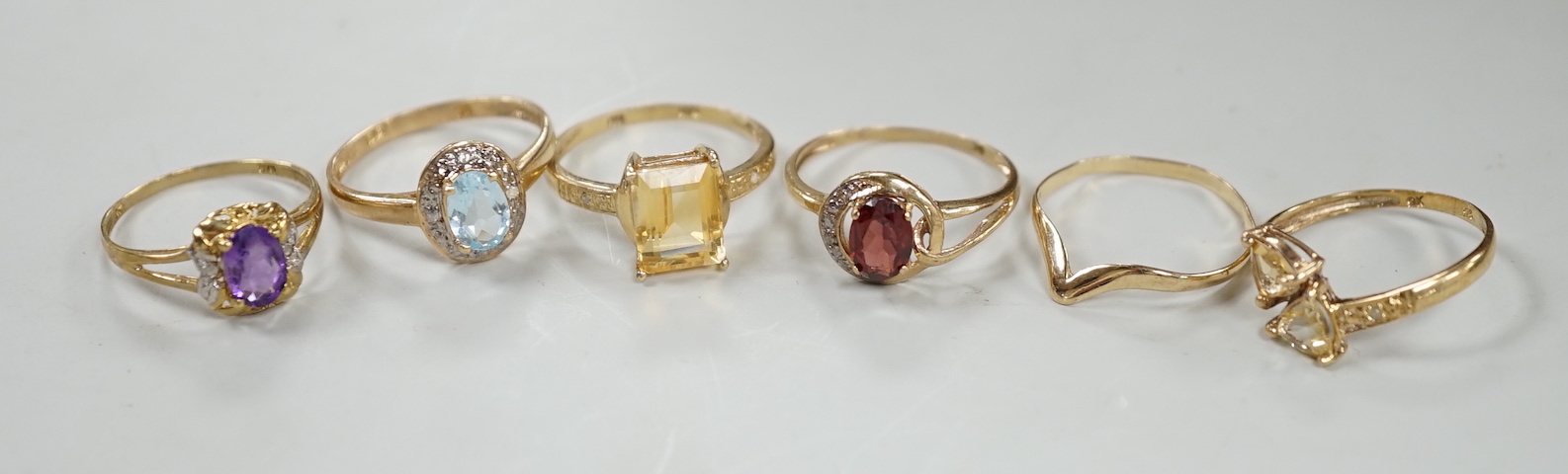 Five assorted modern 375 and gem set rings including amethyst and citrine, together with a 9ct wishbone shaped ring, gross weight 7.6 grams.